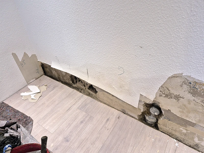 Geöffneter Sockelbereich einer Innenwand zur Schadenfeststellung bei Feuchtigkeit