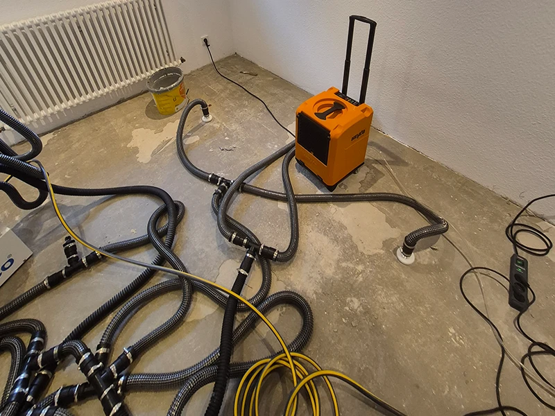 Raum mit laufender Estrichtrocknung und angeschlossenem Schlauchsystem
